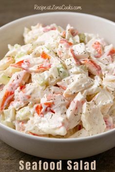 a white bowl filled with coleslaw salad on top of a wooden table next to a fork