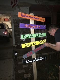 a man standing next to a street sign that has been decorated with different colored signs