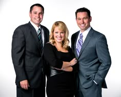 two men and a woman are posing for a photo in front of a white background