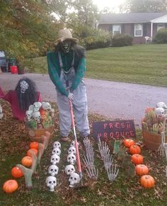 a scarecrow is holding a broom in front of pumpkins and other decorations on the lawn