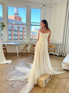 a woman in a white wedding dress standing on a wooden floor next to a window