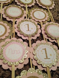 pink and gold cupcake toppers with the number one on them for a first birthday