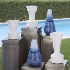 several vases sitting on top of each other in front of a pool and grass