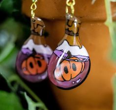 a pair of earrings with painted pumpkins hanging from them