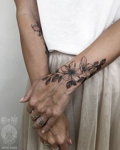 two people holding hands with tattoos on their arms and both have flowers tattooed on them