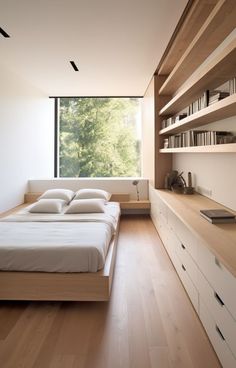 a bed sitting in a bedroom next to a window with lots of books on it