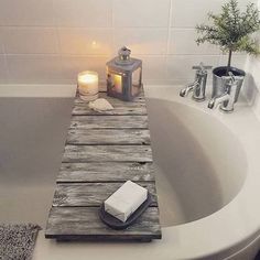 a bath tub with a candle, soap and towel on the edge next to it