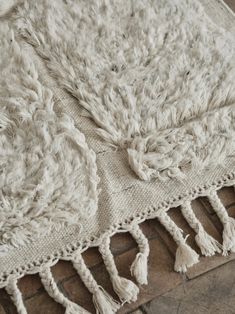 a white rug with tassels on it sitting on top of a brick floor