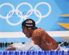 a man swimming in the water with an olympic medal on his cap and goggles