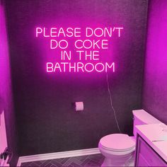 a bathroom with a neon sign above the toilet