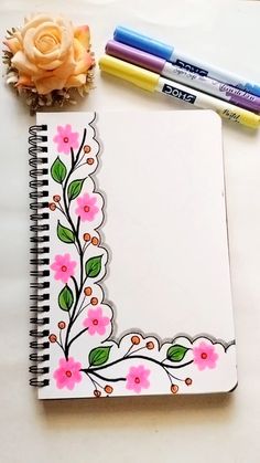 an open notebook with flowers and markers next to it