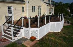 a deck with railings and chairs next to a house