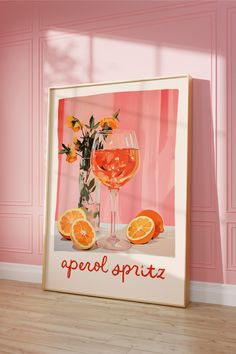 an orange and wine glass sitting on top of a wooden floor next to a pink wall