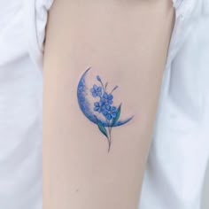 a woman's arm with a blue flower tattoo on the left side of her arm