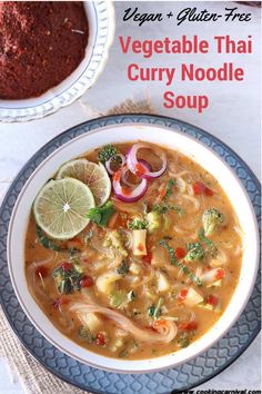 a bowl of vegetable thai curry noodle soup on a plate with a spoon next to it