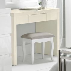 a white vanity table with a stool in front of it