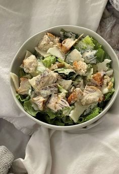 a white bowl filled with salad sitting on top of a bed next to a teddy bear