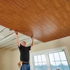 a man is working on the ceiling in an empty room