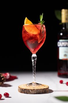 a red drink in a wine glass with an orange garnish on the rim