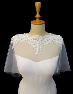 a white wedding dress on a mannequin with a veil over the bustle