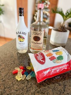 some liquor bottles and candy on a granite counter with a christmas tree in the background