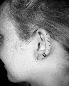 black and white photograph of a woman's ear with tattoos on it