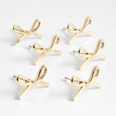 four pairs of gold - plated bow and arrow cufflinks on white background