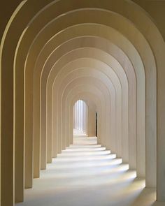 an arched hallway with white walls and columns