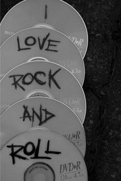 four dvds with graffiti on them sitting in front of a black background and the words love rock and roll written on it