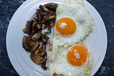 two fried eggs and mushrooms on a white plate