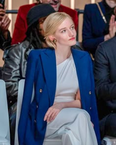 a woman sitting on top of a white chair next to a man in a suit