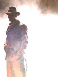 a man in a hat and trench coat standing next to a fire extinguisher