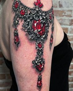 a woman's arm with red jewels on it and an ornate cross in the middle