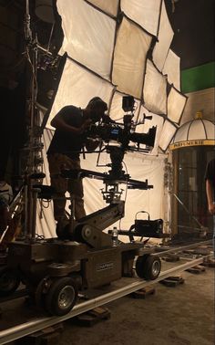 a man standing next to a camera on top of a dolly