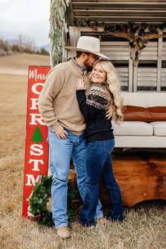 a man and woman standing in front of a christmas sign