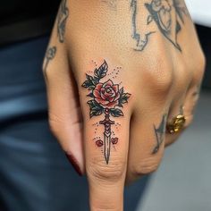 a woman's hand with a rose tattoo on it and a knife in the middle