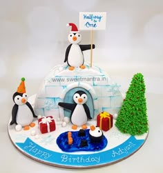 a birthday cake decorated with penguins and presents