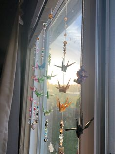 the birds are hanging on the window sill by the curtain rod, which is decorated with beads and glass beads