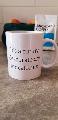 a white coffee mug sitting on top of a counter next to a bag of coffee