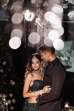 a man and woman standing next to each other in front of a chandelier