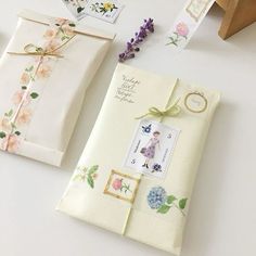 two envelopes decorated with flowers and stamps are on the table next to each other