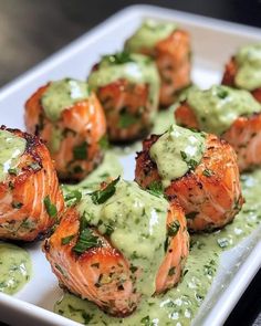 a white plate topped with shrimp covered in green sauce