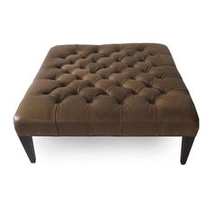 a brown leather ottoman sitting on top of a white floor