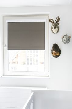 a baby's room with white walls and deer head mounted to the side of the wall