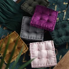 four different colored cushions sitting on top of a rug