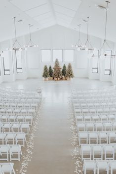 an empty church with white chairs and christmas trees