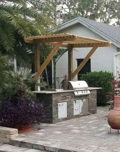 an outdoor bbq and grill area in the back yard with potted plants on either side