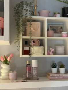 a shelf filled with vases and plants on top of a white counter next to other items