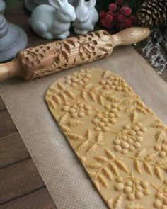 an uncooked pastry on a cookie sheet next to a rolling pin and some bunny figurines