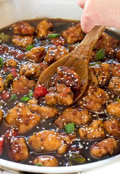 someone is stirring chicken in a pot with sesame seeds